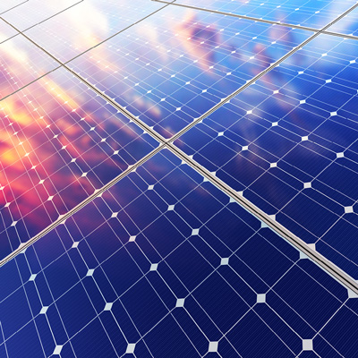 Close-up of solar panel array with some reddish clouds reflected in the dark blue panels.